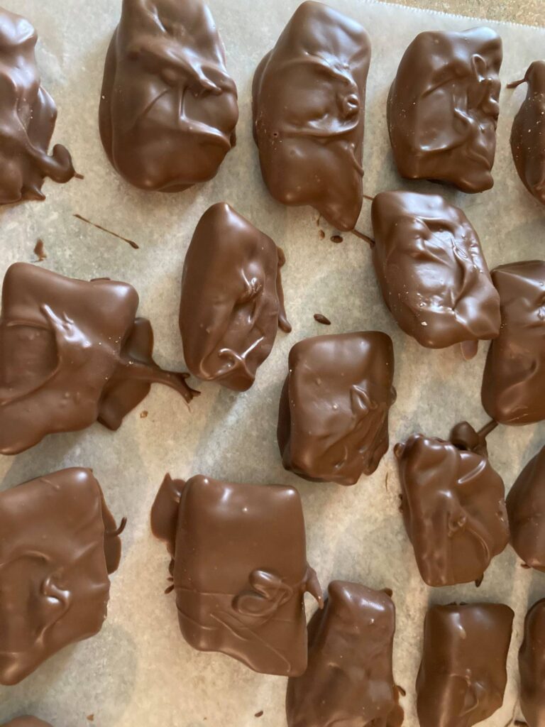 Dipping crunchy peanut butter centers into melted chocolate coating wafers.