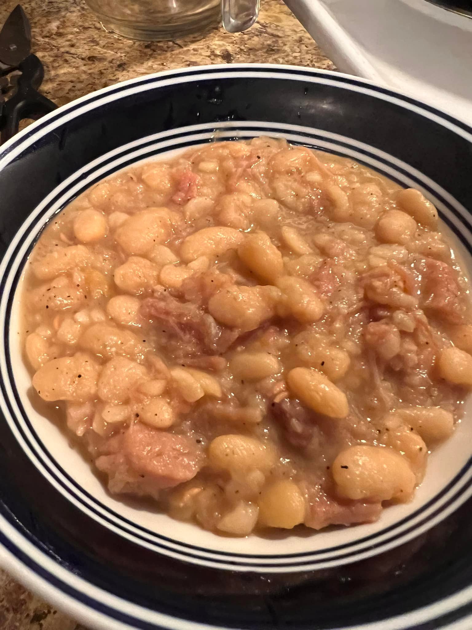 Hearty bowl of homemade ham and bean soup on a kitchen counter.