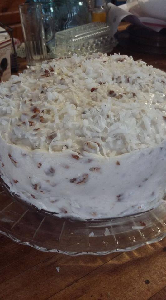 Pouring smooth cream cheese and Coco Lopez icing over a white cake
