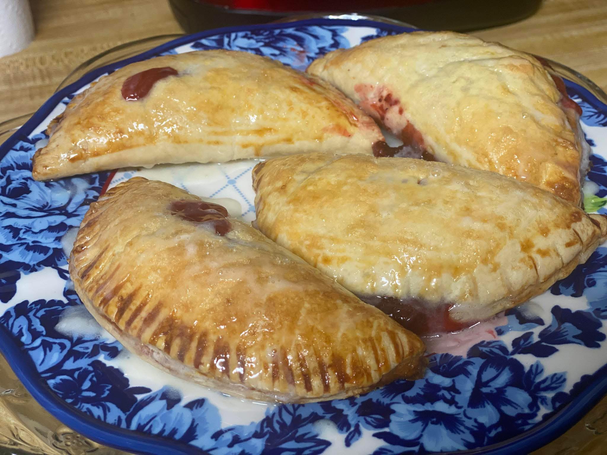 Homemade strawberry turnovers with a glossy egg wash and powdered sugar drizzle.