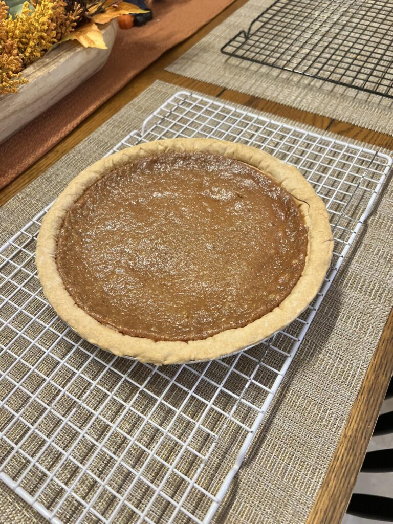 Whole Apple Butter Pie in a flaky crust sitting on a wooden dining table.