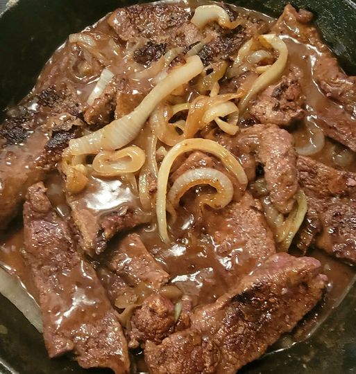 Traditional Southern style liver and onions served in a rustic skillet.