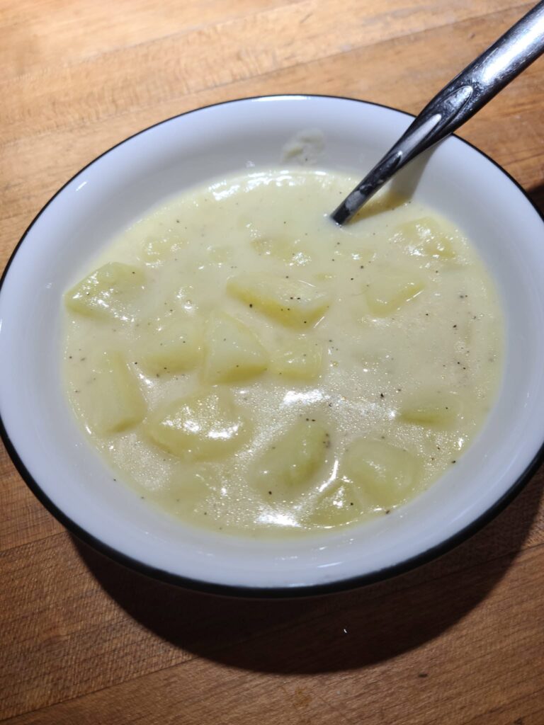 Stirring rich Old Fashioned Potato Soup on the stove.